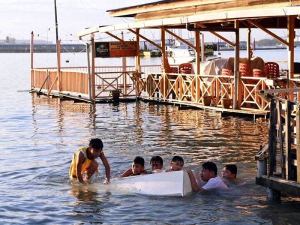Kelihatan segelintir kanak-kanak mengambil kesempatan bermandi-manda di kawasan rumah yang dinaiki air sehingga mencecah paras 5.8 meter berikutan fenomena air laut pasang besar di Perkampungan Nelayan Bagan Hailam, hari ini.
