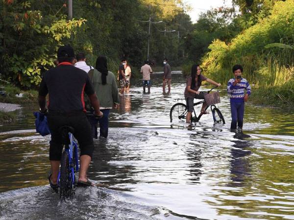 Kelihatan penduduk terpaksa mengharungi air yang membanjiri jalan berikutan fenomena air laut pasang besar di Perkampungan Nelayan Bagan Hailam hari ini.