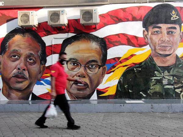 Seorang pejalan kaki melintasi lukisan mural gergasi potret Pemangku Raja Pahang Tengku Mahkota Tengku Hassanal Ibrahim Alam Shah Al-Sultan Abdullah, Menteri Besar Pahang Datuk Seri Wan Rosdy Wan Ismail dan Ketua Pengarah Kesihatan Tan Sri Dr Noor Hisham Abdullah, hari ini.