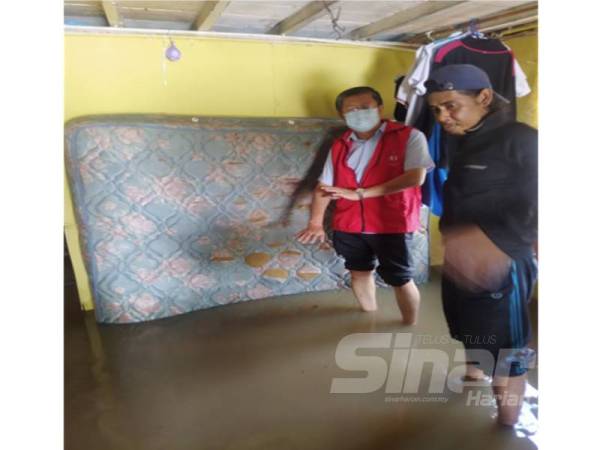 Kok Yew (kiri) melihat keadaan rumah Zulkifli di Kampung Tanjung Seri, mukim Derga, Alor Setar dinaiki air sejak Khamis lepas.