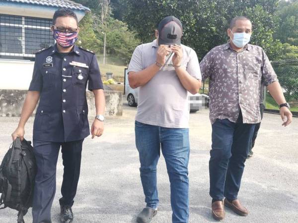 Tertuduh (tengah) diiring polis ketika tiba di Mahkamah Majistret Kuala Pilah hari ini.
