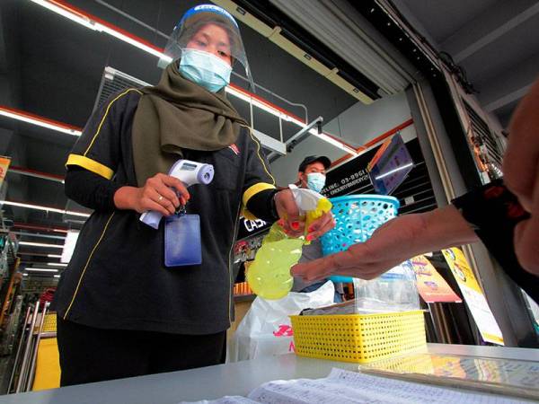 Pekerja kedai serbaneka Julie Shaliza Mizan, 25, memberi cecair pembasmi kuman (hand sanitizer) kepada salah seorang pelanggan sebelum dibenarkan masuk ke dalam premis tersebut.