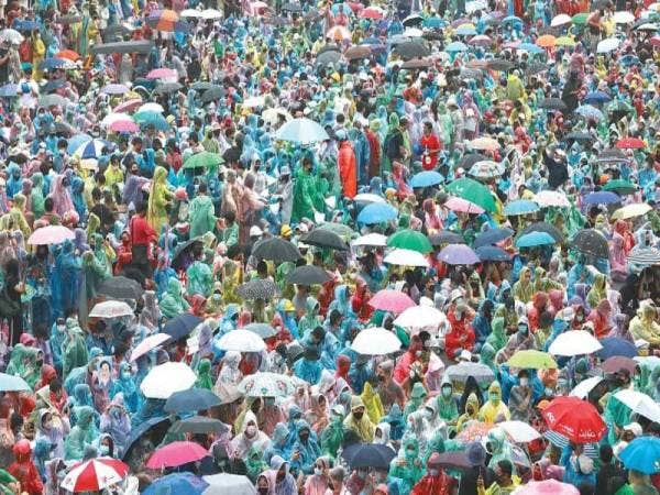 Ribuan penunjuk perasaan menggunakan payung dan memakai ponco dalam tunjuk perasaan meminta pembaharuan ke atas institusi beraja di Bangkok pada Ahad lalu. - Foto AFP