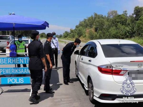 Mohd Haris ketika membuat pemeriksaan kenderaan yang melakukan rentas sempadan di sekatan jalan raya Jalan Papar Lama, Penampang semalam. - Foto IPD Penampang