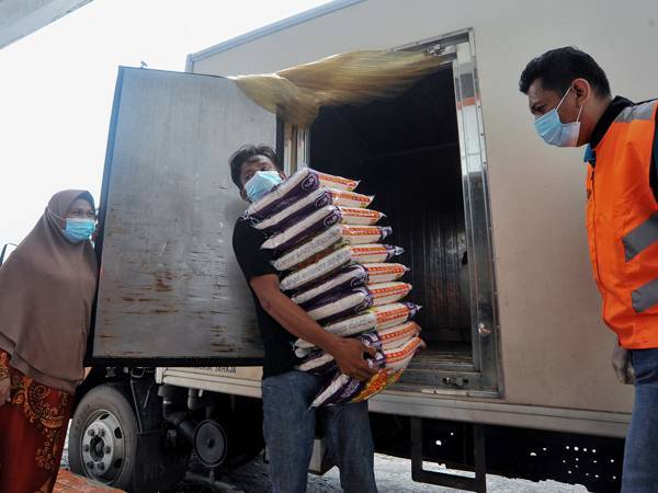 Petugas serta penyumbang bantuan kit makanan asas sibuk mengumpul barangan makanan di pusat pengumpulan Jabatan Kebajikan Masyarakat Labuan sebelum diagihkan ketika tinjuan hari ini. - Foto Bernama