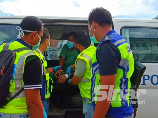 Anggota polis terpaksa memujuk dan menenangkan tertuduh yang didakwa di Mahkamah Majistret, Pasir Puteh sebelum membawanya masuk ke mahkamah.