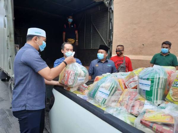 Mohd Afifi (kiri) menyerahkan sumbangan kepada Mohamed Jusoh (dua dari kiri) di hadapan Penjara Pulau Pinang di Georgetown hari ini.