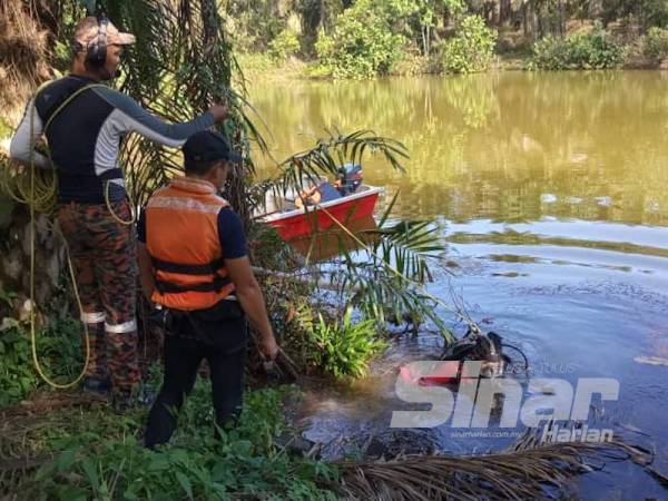 Anggota bomba mengangkat mayat seorang remaja lelaki selepas ditemukan kira-kira 2 meter dari tempatnya lemas di Sungai Linggiu, Felda Linggiu, Kota Tinggi hari ini.
