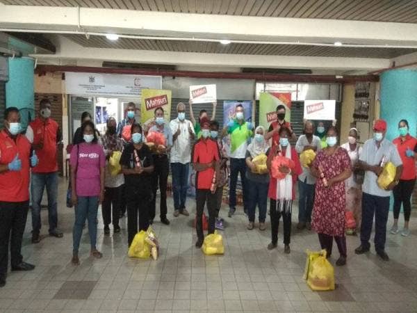 Mohd Jazri dan Charles bersama sebahagian penerima dari komuniti Melayu yang hadir pada majlis ringkas pengedaran barangan keperluan asas oleh Food Bank di Perhentian Bas Pelabuhan Klang semalam.