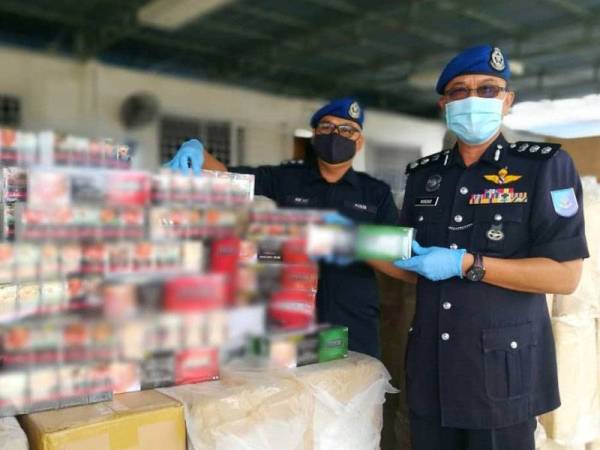 Norzaid (kanan) bersama pegawainya menunjukkan rokok seludup yang dirampas dalam serbuan di hutan bakau di Sungai Bukit Keluang, Besut, Terengganu awal pagi tadi.