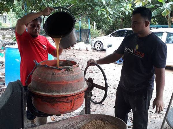 Abdul Razak (kiri) dibantu pekerjanya, Mohammad Idham Abdulllah bagi menghasilkan dedak ayam di ladangnya di Kampung Perik, Kuala Nerang semalam.