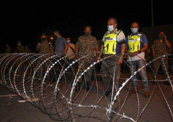 Che Zakaria (dua dari kanan) melihat kawat duri yang dipasang di sekitar bangunan di Putra Point, Nilai yang terlibat dengan PKPD malam tadi.
