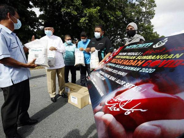 Pengerusi Jawatankuasa Agama dan Pendidikan negeri Datuk Najmi Ahmad (dua, kiri) menyampaikan bantuan makanan kepada Pengarah Penjara Alor Setar Raja Mohd Amazon Raja Daud (kiri) hasil sumbangan pihak Yayasan Dakwah Islamiah Malaysia (YADIM) pada Program Musa'adah YADIM di hadapan pos pengawal Penjara Alor Setar di sini hari ini.