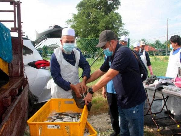 Syed Abu Hussin Hafiz (kiri) memilih ikan kembung untuk diedarkan secara percuma kepada para penduduk pada program Kedai Bergerak Parlimen Bukit Gantang di Taman Mewah, Kamunting hari ini. - Foto Bernama