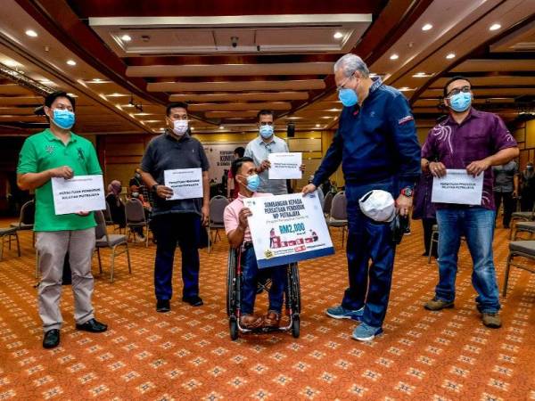 Annuar beramah mesra dengan wakil penduduk, Khairul Anam (berkerusi roda) dan penerima lain pada majlis Sumbangan Wilayah Cakna 3.0 di Kompleks Perbadanan Putrajaya (PPj), Putrajaya hari ini. - Foto Bernama