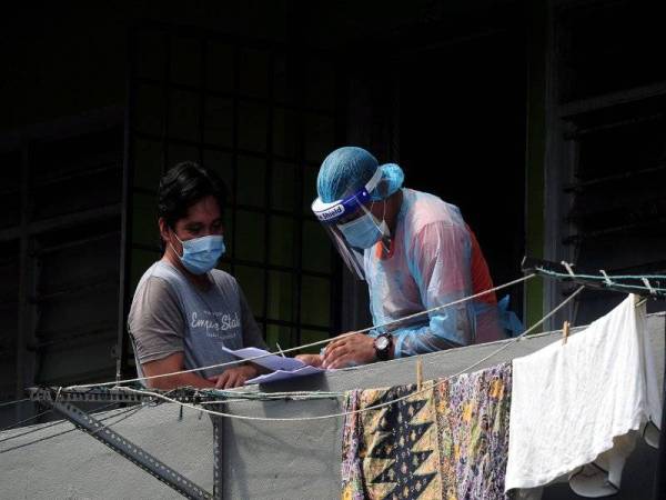 Petugas barisan hadapan melakukan pemeriksaan terhadap penduduk ketika tinjauan di kawasan Perintah Kawalan Pergerakan Diperketat (PKPD) di Flat Sungai Emas, Kuala Langat hari ini. - Foto Bernama