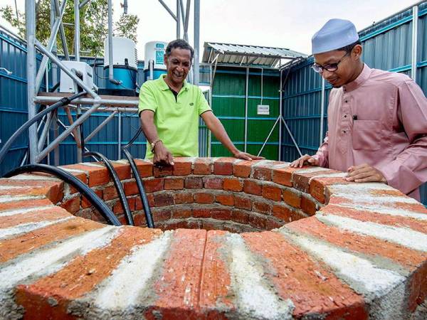 Penduduk Kampung Meranti Abd Hadi Omar, 67, (kiri) bersama Ahmad Syakir Mohd Massuruddin menunjukkan telaga dipercayai dibina oleh Hang Tuah ketika ditemui Bernama baru-baru ini.- Foto Bernama