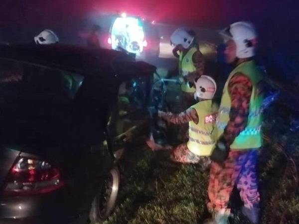 Anggota bomba mengeluarkan mangsa yang tersepit dalam kereta. - Foto Bomba Perak