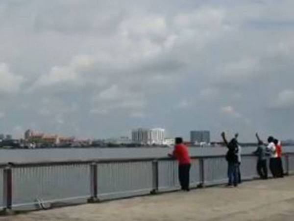Tangkap layar video rakyat Malaysia menyaksikan ahli keluarga mereka melambai-lambai di sebelah perairan negara di jeti Woodlands Waterfront Park pagi ini. - Bernama