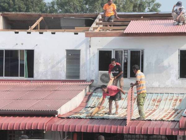 Penduduk sedang membaiki bumbung rumah yang rosak akibat ribut malam semalam.