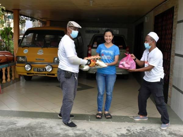 Kelihatan petugas sukarelawan mengagihkan bantuan makanan kepada penduduk Taman Semarak yang terjejas akibat Perintah Kawalan Pergerakan Diperketatkan (PKPD) yang dikenakan di kawasan mereka sejak Isnin lepas, ketika tinjauan semalam. - Foto Bernama