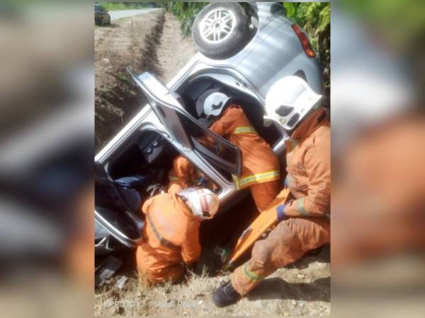 Anggota dari Balai Bomba dan Penyelamat Bidor mengeluarkan mangsa yang tersepit di bahagian hadapan kenderaan.