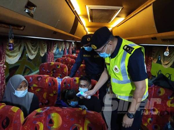 Zulkarnain memeriksa suhu salah seorang penumpang bas ekspres dalam operasi pematuhan SOP di Terminal Bas MBKT Kuala Terengganu malam tadi.