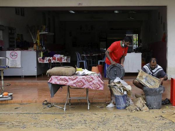 Pengusaha restoran makanan L Rajoolingam dan S Muthosamy (kiri) mengasingkan barangan yang rosak berikutan premis perniagaannya dimasuki banjir lumpur susulan hujan lebat sejak pukul 12.45 malam tadi ketika tinjauan foto Bernama di sekitar Rantau hari ini.