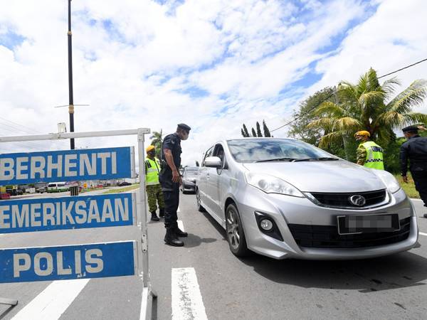 Anggota polis membuat sekatan jalan raya di Jalan Sabindo-Papar berikutan perintah larangan rentas daerah bagi mengelak penularan Covid-19. - Foto Bernama