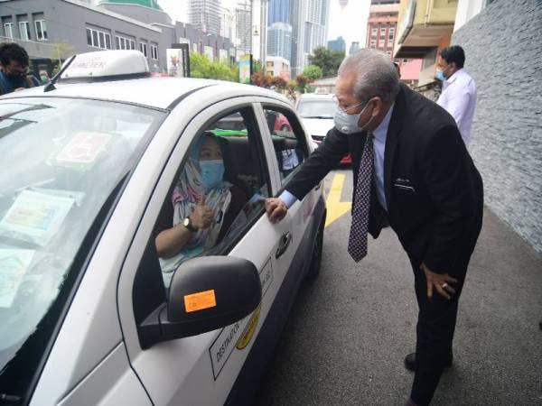 Annuar menyantuni pemandu teksi yang menerima bantuan makanan asas secara pandu lalu di Laman Yayasan Wilayah Persekutuan Kampong Bharu di Kuala Lumpur hari ini.