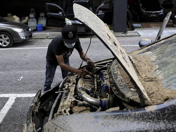 Pemilik kedai kecantikan kereta Nik Mohd Shaffrizal Yusoff melakukan kerja-kerja pengasingan tanah lumpur pada kereta pelanggan yang terjejas berikutan banjir kilat yang berlaku baru-baru ini ketika tinjauan di premis perniagaannya Kechik Pro Detailing di Forest Height, hari ini.