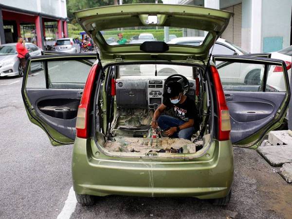 Pemilik kedai kecantikan kereta Nik Mohd Shaffrizal Yusoff melakukan kerja-kerja pengasingan tanah lumpur pada kereta pelanggan berikutan ditenggelami banjir kilat yang berlaku baru-baru ini ketika tinjauan di premis perniagaannya Kechik Pro Detailing di Forest Height, hari ini. 