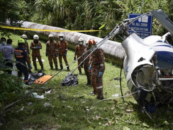 Anggota Jabatan Bomba dan Penyelamat kelihatan membawa keluar dua mayat dari sebuah helikopter yang terhempas di kawasan Taman Melawati Ampang hari ini. - Foto Bernama