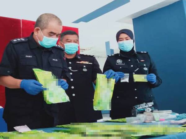 Noorzainy (kiri) menunjukkan dadah yang dibungkus semula ke dalam bungkusan jus limau sebelum dijual kepada pelanggan.