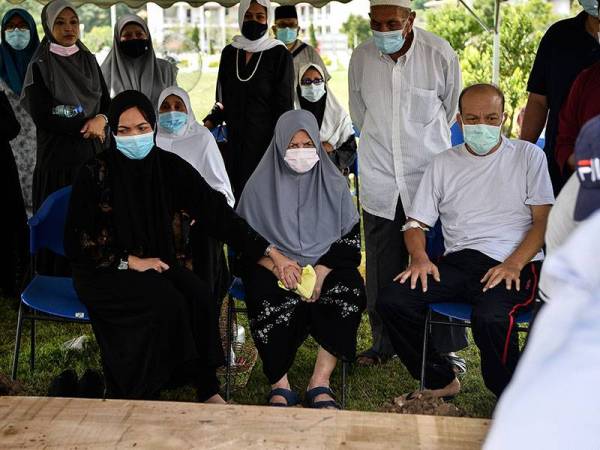 Ibu kepada jenazah mangsa helikopter terhempas Intan Omar ,76, (duduk tengah) melihat pengebumian anaknya iaitu Allahyarham Komander (B) Mohamed Sabri Baharom di Tanah Perkuburan Islam Raudhatul Sakinah hari ini. Foto: Bernama
