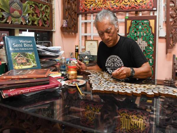 Pemilik Seni Kayu Warisan, Burhan Ashari melakukan proses mewarna berkonsepkan Melayu pada ukiran kayu ketika ditemui di bengkelnya di Kampung Pulau Rusa. - Foto Bernama
