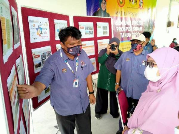 Siti Ashah mendengar penerangan oleh kakitangan Keda tentang kejayaan yang dicapai penduduk dalam projek Prospek Sidam di Pusat Kegiatan Ekonomi (PKE) Sidam Kanan, Padang Serai semalam.