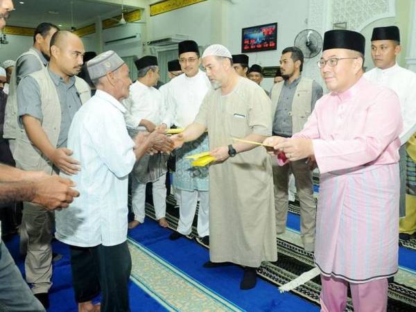 Sultan Muhammad V (dua dari kiri) menyempurnakan pengurniaan zakat kepada asnaf anjuran Majlis JP Kelantan di Masjid Mukim Pangkal Meleret, Machang.