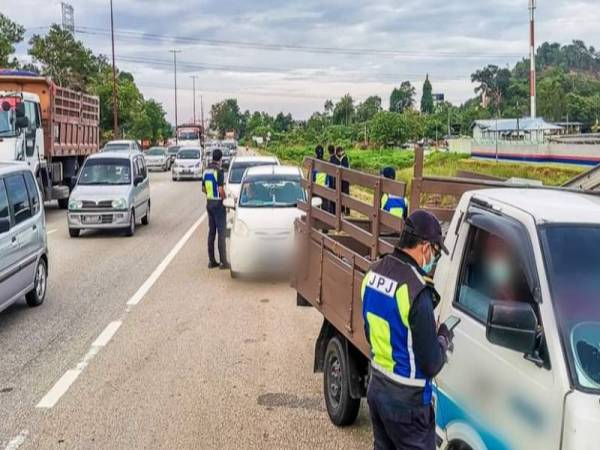 Anggota URB JPJ Pahang mengeluarkan kompaun kepada pengguna jalan raya yang didapati memotong barisan menggunakan lorong kecemasan pada operasi Ops Tujuh Kesalahan Utama di Jalan Pintasan Kuantan semalam. - Foto JPJ PAHANG