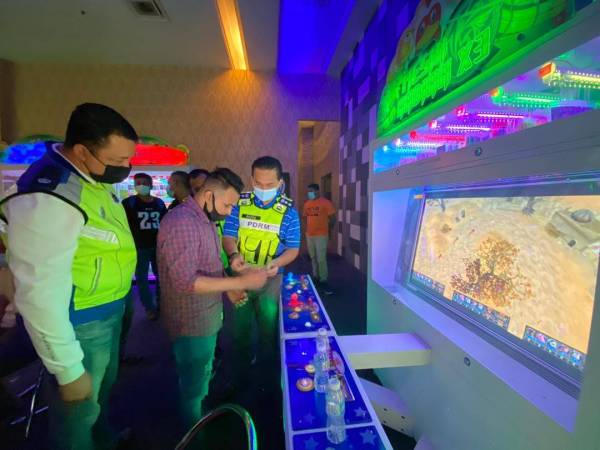 Razali (kanan) melihat antara mesin pertaruhan perjudian yang disediakan di premis yang beroperasi di sebuah pusat beli-belah di Seri Kembangan malam tadi.