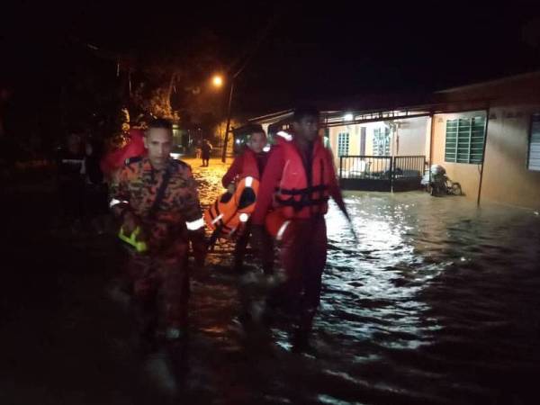 Anggota bomba membantu memindahkan penduduk selepas rumah penduduk dinaiki air.
