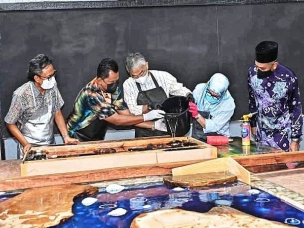 Al-Sultan Abdullah (tengah) bersama Tunku Azizah tidak ketinggalan memberi sentuhan kreatif kepada produk kraf kayu ketika berada di Pusat Inkubator Kraf Temerloh hari ini. - Foto Istana Negara