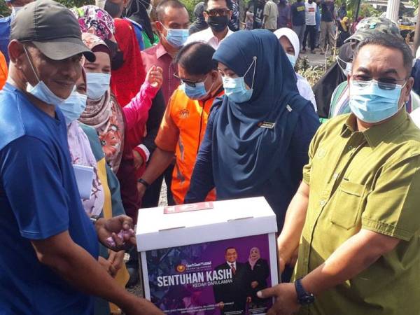 Radzian (kiri) menerima sumbangan yang disampaikan sendiri Muhammad Sanusi ketika turun melawat mangsa kebakaran di Kampung Alor Madi, Anak Bukit hari ini.