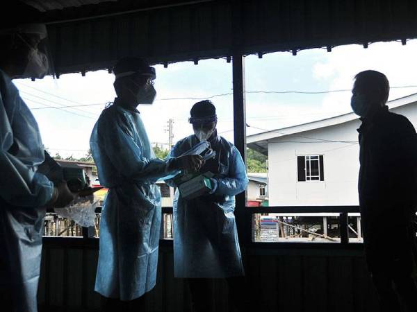 Pengarah Jabatan Kesihatan Labuan Dr Ismuni Bohari (dua, kiri) menyerahkan pelitup muka kepada salah seorang penduduk pada Program Tinjauan Mesra (Walkabout) bagi mendekati penduduk setempat dan memberi pendidikan kesihatan disamping melakukan pemantauan dalam komuniti susulan penularan wabak COVID-19 di Kampung Bebuloh Laut hari ini. 