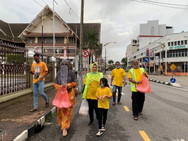 Sukarelawan berjalan di sekitar bandar Kota Bharu untuk mengagihkan bungkusan makanan petang semalam.