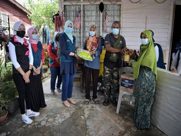 Rina (tiga, kiri) menyerahkan bantuan kepada mangsa banjir, Latifah Ahmad, 48, (tiga, kanan), bersama suaminya Mohd Nor Waled, (dua dari kanan), di Pekan Batu 18, Hulu Langat hari ini. Foto Bernama