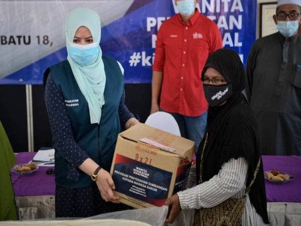 Rina (kiri) menyerahkan bantuan kepada seorang mangsa banjir, Esah Mohd Din (kanan) pada majlis penyerahan sumbangan barangan keperluan asas kepada mangsa banjir daerah Hulu Langat di Balai Raya Pekan Batu 18, Hulu Langat hari ini. Foto Bernama