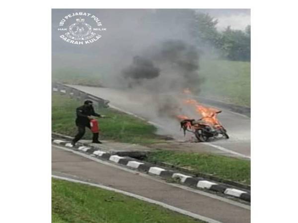 Mohd Redzuan memadam kebakaran sebuah motosikal yang ditunggang tiga beranak di laluan motosikal di Plaza Tol Senai, Kulai hari ini.- Foto Polis Daerah Kulai