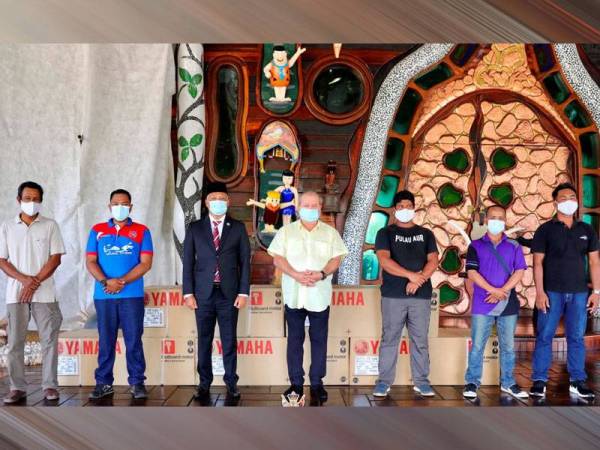Sultan Ibrahim (tengah), Asman (tiga dari kiri) dan lima nelayan yang menerima sumbangan enjin bot daripada Sultan Johor di pekarangan Istana Flintstones, Mersing hari ini.
