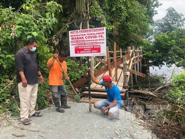 Papan tanda pemberitahuan berhubung penutupan Jambatan Denai Sungai Pengkalan Datu didirikan di pintu masuk oleh pekerja pembinaan sambil diperhatikan Zamri Awang (kiri) di Kampung Pulau Tengah, Kubang Kerian, Kota Bharu hari ini.